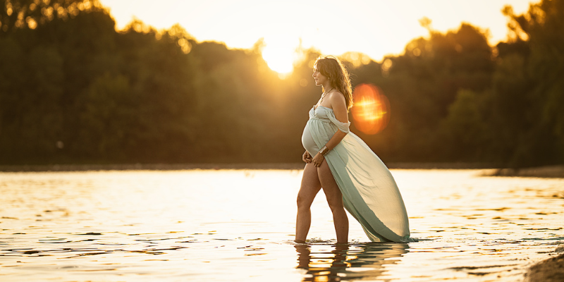 Femme enceinte marchant dans l’eau au coucher du soleil